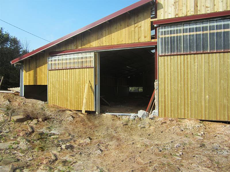 Hangar avec bardage en bois et tôles translucides en façade