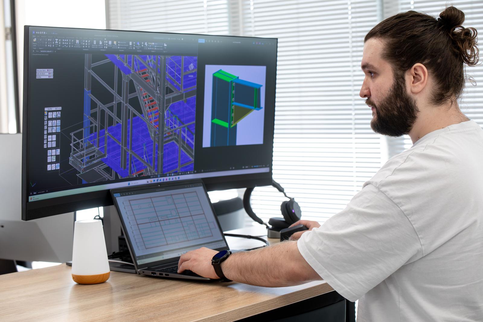 Ingénieur du bureau d'études travaillant sur un modèle 3D de charpente métallique sur double écran, Steel Shed for Business
