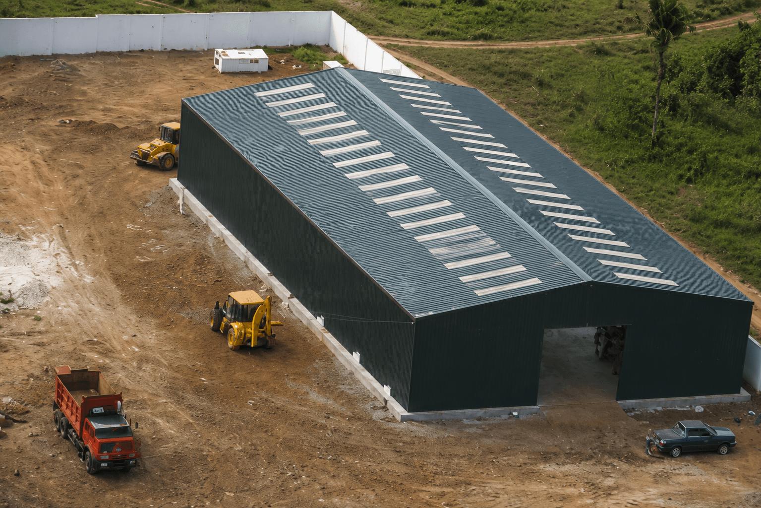 Vue aérienne d'un bâtiment métallique anthracite en cours de montage sur chantier avec engins, Steel Shed for Business