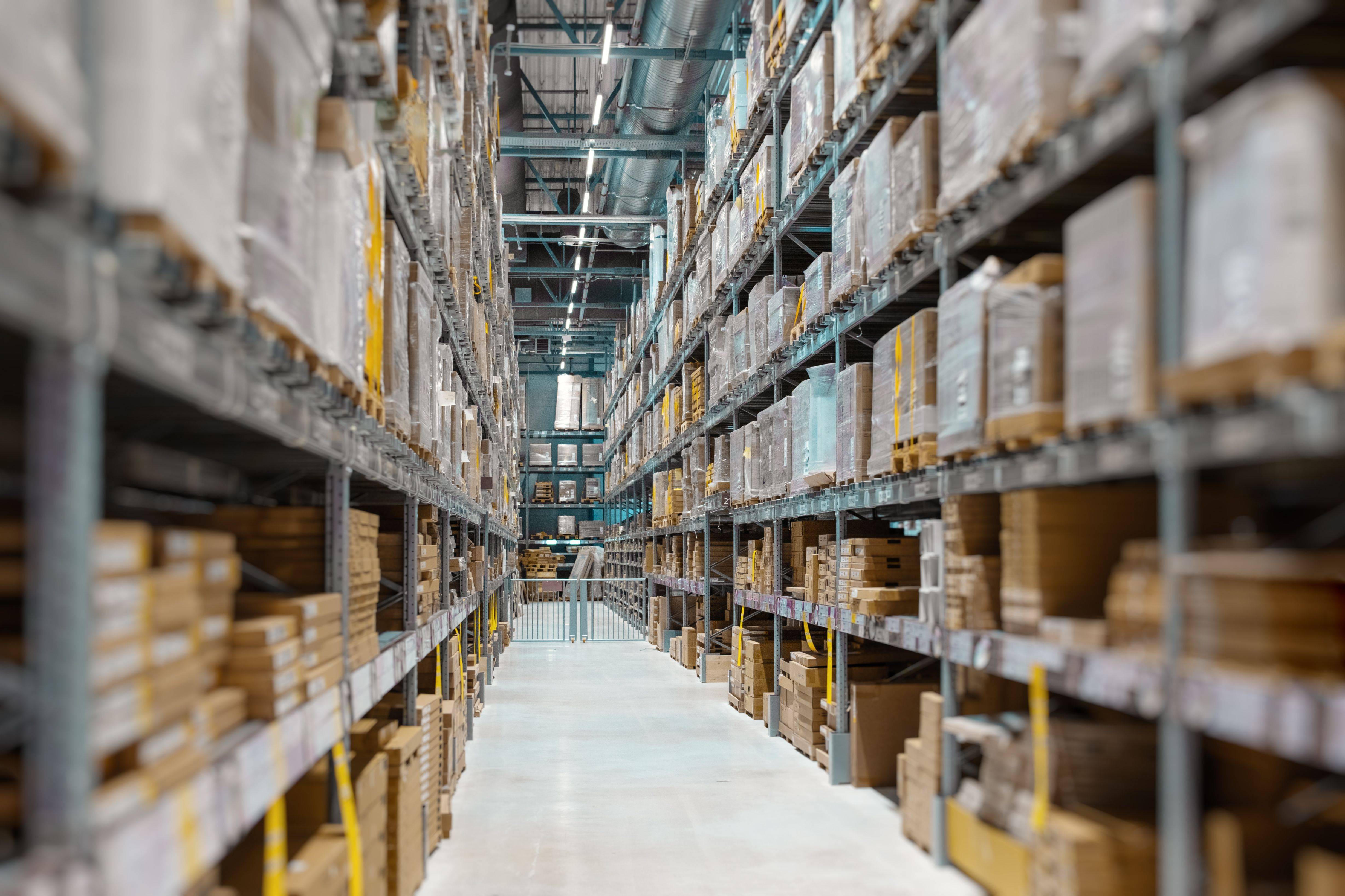 Allée d'un entrepôt de grande hauteur avec rayonnages remplis de marchandises