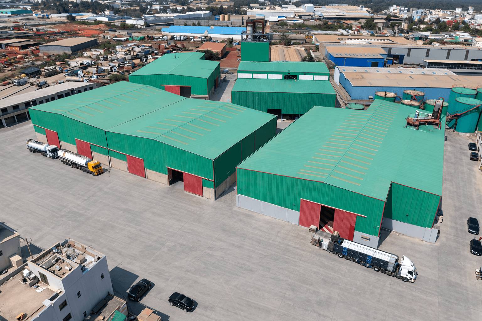 Vue aérienne d'un complexe industriel de bâtiments métalliques à toiture verte avec camions-citernes, Steel Shed for Business