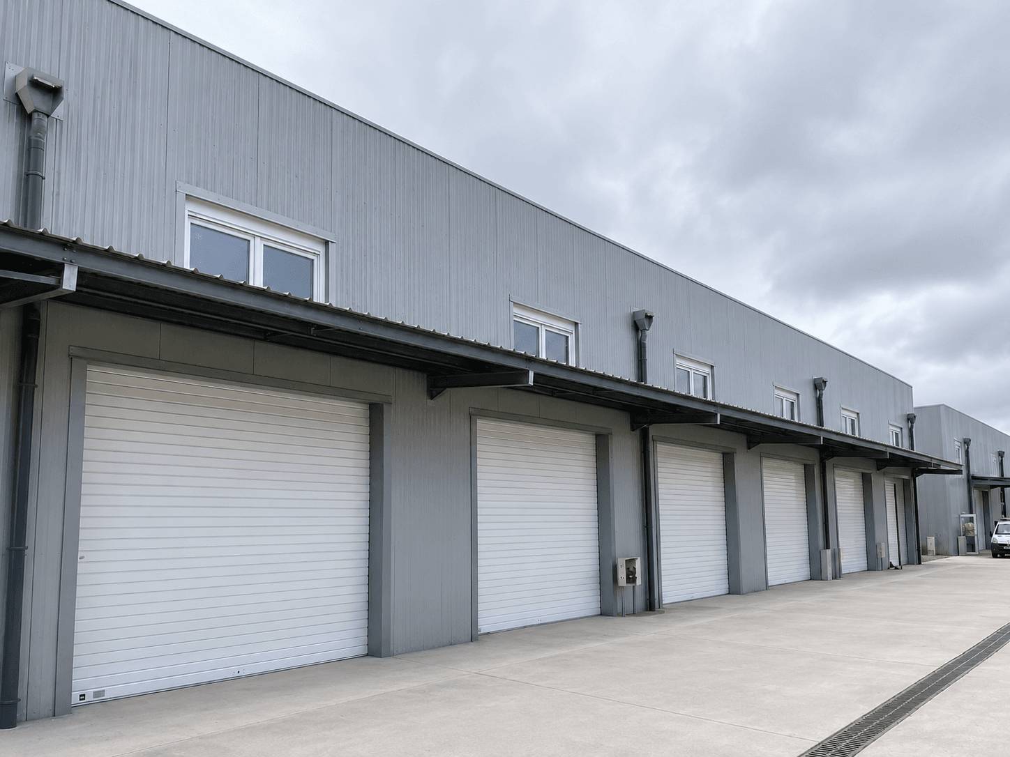 Entrepôt logistique métallique gris avec rangée de portes et auvent de quai, galvanisé à chaud, Steel Shed for Business