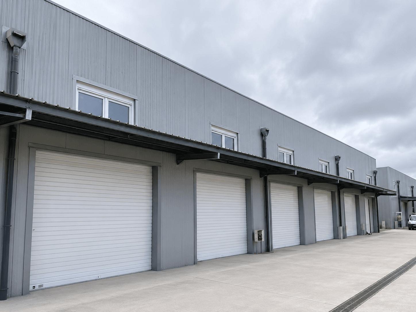 Entrepôt logistique métallique gris avec rangée de portes et auvent de quai, galvanisé à chaud, Steel Shed for Business